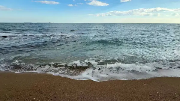 Yumuşak dalgalar kumlu kıyıya vurur, rahatlamak ve doğa severler için mükemmel bir ortam yaratır.