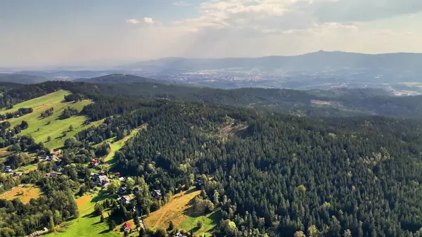 Sersemletici hava görüntüsü güzel bir şekilde sergileniyor yemyeşil tepeler ve dalgalı gökyüzünün altında yuvarlanan vadiler.