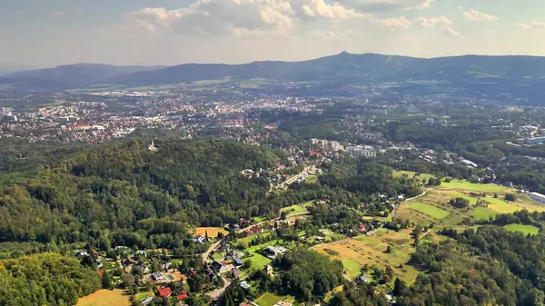 Alttaki yemyeşil manzarayı ve şehri görüntülemek, doğa ve kentsel temalar için idealdir..