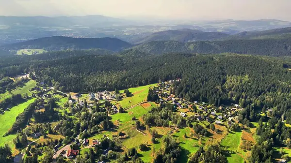 Çarpıcı hava manzarası, dağınık evleri ve yoğun ormanları olan yemyeşil bir vadiyi güzel bir şekilde yakalıyor.