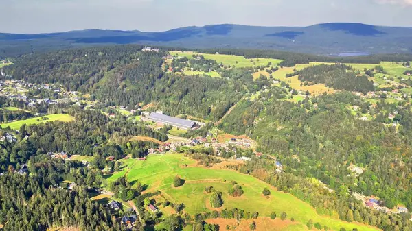 Göz kamaştırıcı bir hava perspektifi, berrak bir gökyüzünün altında uzanan dingin dağların yanında yemyeşil tepeler sergiliyor.