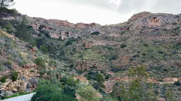 Huzurlu bir su kütlesine bakan nefes kesici dağ manzarası çarpıcı mavi gökyüzü ile çevrili.