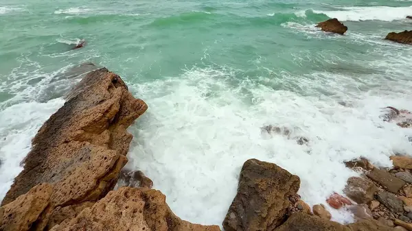 Huzurlu bir sahnede, dalgalar bu güzel kıyı manzarası içindeki kayalık kıyılara hafifçe çarpıyor.