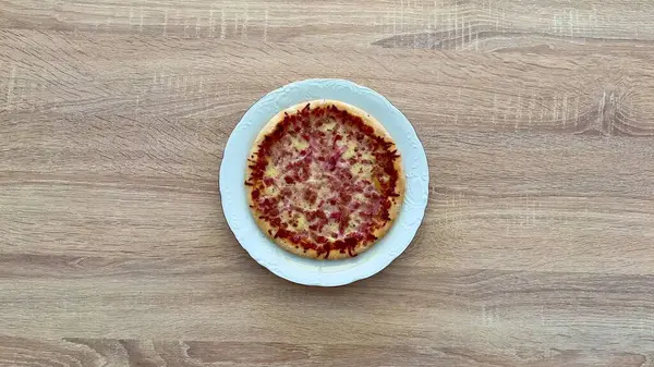Lezzetli ve cezbedici bir dilim pizza temiz beyaz bir tabakta sunuluyor. Atıştırmalık ya da yemek için mükemmel.