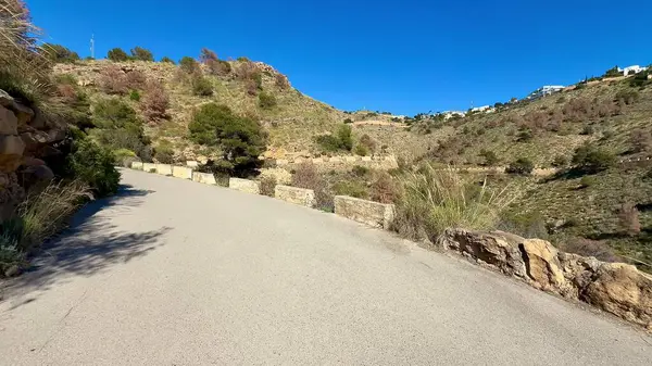 Kayalık kenarlar ve bereketli yamaçlarla dolu güzel bir kıyı yolu manzarası.