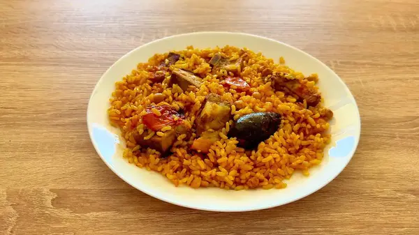 Lezzetli ve canlı bir tabak Jollof pilavı, güzel bir tavuk ve bir dizi taze sebze.