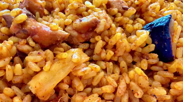 Canlı bir tabak Jollof pilavı, içinde taze tavuk ve renkli sebzeler var, her yemek için mükemmel.