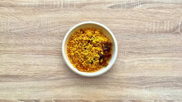 Lezzetli bir yemek için mükemmel baharatlar, fasulyeler ve tuzlu parçalar içeren canlı bir kase sarı pirinç..