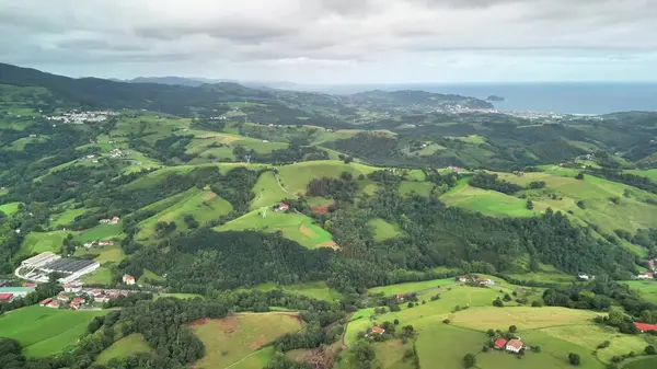 Sersemletici ve nefes kesici yuvarlanan yeşil tepelerin hava görüntüsü bulutlu bir gökyüzünün altında kıyılarla güzel bir şekilde buluşuyor.