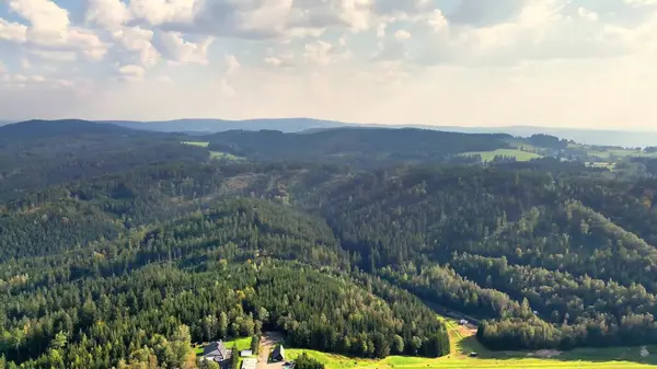 Kesinlikle nefes kesici bir hava manzarası dalgalı bir gökyüzünün altındaki kayan tepeleri ve yemyeşil ormanları gösteriyor.