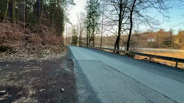 Ağaçları, asfalt yolu ve güzel doğal çevreyi gözler önüne seren sakin ve huzurlu bir yol manzarası.