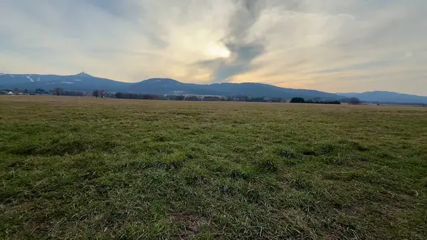 Muhteşem dağlarla dolu engin ve açık bir arazinin nefes kesici ve çarpıcı manzarası güzel bir günbatımı gökyüzünün altında.