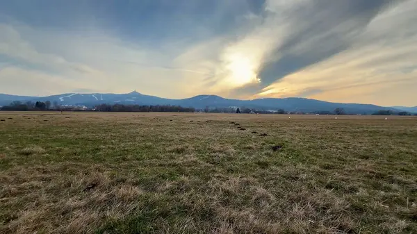 Uçsuz bucaksız tarlaların ve muhteşem dağların göz kamaştırıcı günbatımı gökyüzünün altında nefes kesici ve görkemli bir manzarası.