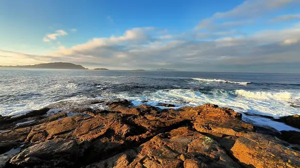 Nefes kesici bir manzara dalgaları sergiliyor dalgalar engebeli kayalara çarpıyor deniz kenarında canlı bir gündoğumu sırasında