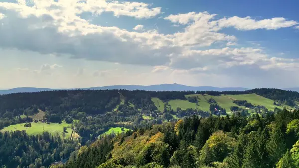 Göz kamaştırıcı ve resimli bir manzara. Yuvarlanan tepeler, yemyeşil ağaçlar ve güzel bulutlu bir gökyüzü.