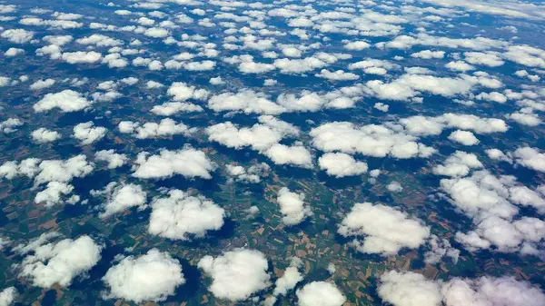 Çarpıcı bir hava perspektifi, güzel, pofuduk bulutları yakalar ve verimli kırsal bölgede zarafetle sürüklenir.
