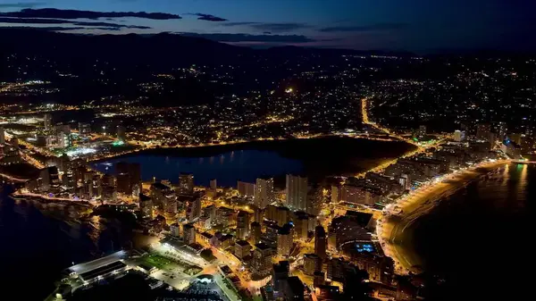 Canlı bir sahil şehrinin hava manzarası gece aydınlanır, güzel ışıklar ve manzaralar sergilenir..