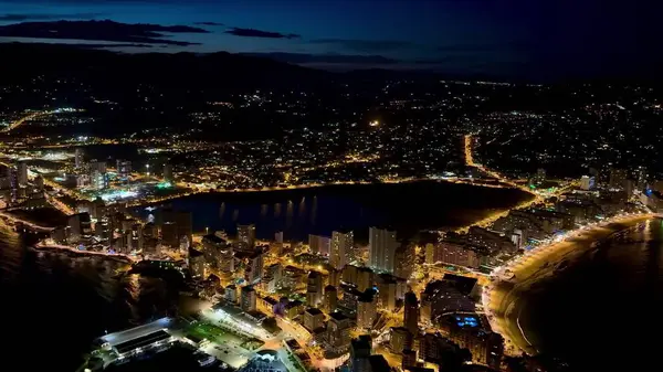 Canlı bir sahil şehrinin nefes kesen şehir ışıklarıyla güzel aydınlatılmış nefes kesici bir hava manzarası.