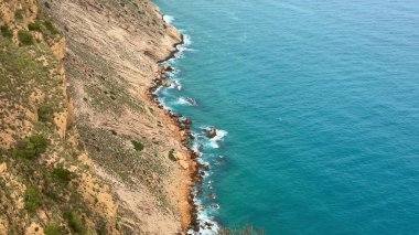 Sakin mavi sularla buluşan kayalık kıyı şeritlerinin çarpıcı manzarasını tecrübe edin. Güzellik arayan doğa aşıkları için mükemmel.