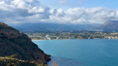 Güzel bir şekilde sergilenen nefes kesici kıyı manzarası dingin sular, yemyeşil tepeler ve büyüleyici bir ufuk çizgisi.