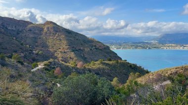 Muhteşem bir gökyüzünün altında görkemli tepelerle çevrili nefes kesen sakin bir su manzarası.