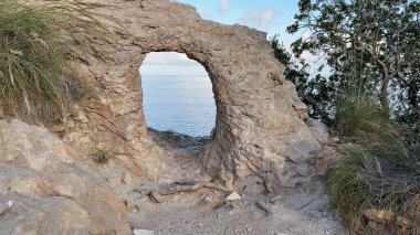 Bereketli yeşillik ve huzurlu sularla çevrili nefes kesici doğal bir kemer içeren nefes kesici bir kaya oluşumu.