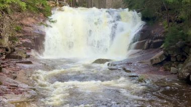 Nefes kesici bir şelale engebeli kayaların üzerinde zarifçe şelale gibi süzülüyor, yemyeşil yeşilliklerle sarmalanıyor.