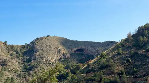 Nefes kesen dağ manzarası geniş mavi gökyüzünün altında tepeler ve canlı yapraklar sergiliyor.