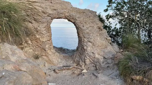Bereketli yeşillik ve huzurlu sularla çevrili nefes kesici doğal bir kemer içeren nefes kesici bir kaya oluşumu.