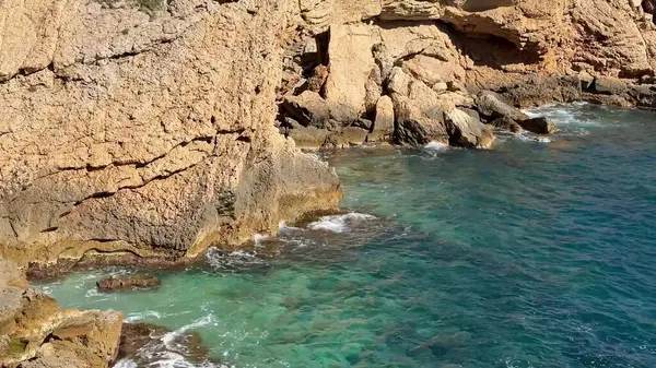 Okyanusun dingin, turkuaz sularıyla buluşan kayalık kıyıların nefes kesici ve büyüleyici görüntüsünü deneyimleyin.