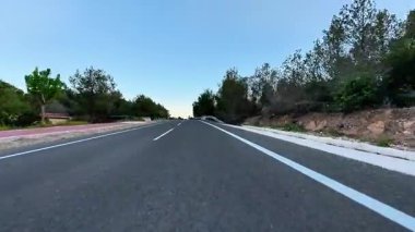 Berrak mavi gökyüzünün altındaki yemyeşil yemyeşil ile çevrili pürüzsüz asfalt bir yolun olağanüstü büyüleyici manzarası.