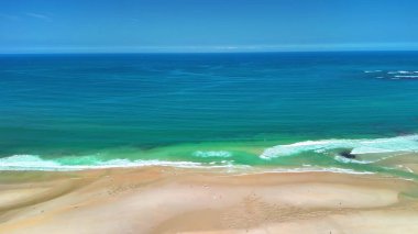 Nefes kesici hava manzarası kumlu bir kumsalın sakin güzelliğinin canlı okyanusla buluşmasını yakalıyor..