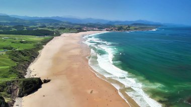 Çevresinde berrak turkuaz suları, dalgaları ve yemyeşil yemyeşil suları olan muhteşem bir sahil manzarası.