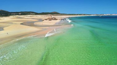 Havadan bakıldığında berrak turkuaz suları ve ışıldayan altın kıyıları olan sakin bir sahil görünüyor.