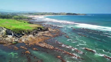Sersemletici kayalık kıyı şeridinin nefes kesici manzarası berrak mavi gökyüzünün altındaki dingin turkuaz sularla birleşmiş.