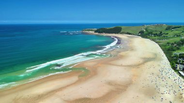 Titreyen turkuaz suları ve altın kumları davet eden sakin bir plajı gösteren nefes kesici bir manzara.
