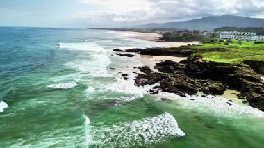 Muhteşem bir sahil manzarası. Dalgalar, kayalık kıyılara ve kumsallara çarpıyor.