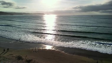 Nefes kesici bir günbatımı, sakin okyanus dalgalarını yansıtıyor, doğa ve seyahat teması için mükemmel.