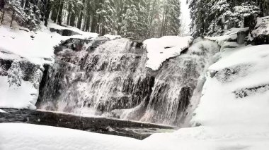 Nefes kesici bir şelale, sakin bir kış ortamında sersemletici bir kar manzarasında zarifçe çağlıyor.