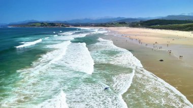 Bir hava sahili dalgalar ve güneşlenmelerle dolu muhteşem bir sahili yakalar ve sahildeki günlerinin tadını çıkarır.