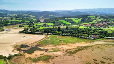 Havadan bakıldığında yemyeşil ve yuvarlanan tepeler arasında kurumuş bir nehir yatağı görünüyor. Nefes kesen güzellikleri vurguluyor.