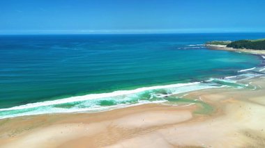 Muhteşem bir sahil manzarası ve açık mavi gökyüzünün altında dalgalar doğa severler ve açık hava meraklıları için mükemmel.