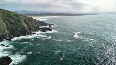 Çarpışan dalgalar ve yemyeşil kayalıklarla dolu nefes kesici kıyı manzaraları gökyüzüne doğru ulaşıyor.
