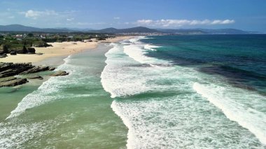 Sersemletici dalgalar durmaksızın sakin bir plaja çarpıyor ve yanında da doğal bir zemin var.