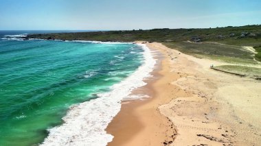 Nefes kesici bir hava manzarası sakin bir plaj sahnesi yakalıyor, büyüleyici turkuaz sular ve altın kum sergiliyor.