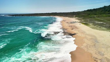 Bu nefes kesici hava fotoğrafında turkuaz dalgalar ve altın kumlarla el değmemiş bir kumsal keşfedin.