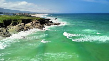 İnanılmaz güzel bir kıyı manzarası, berrak mavi gökyüzünün altında turkuvaz suları ve engebeli uçurumları sergiliyor.
