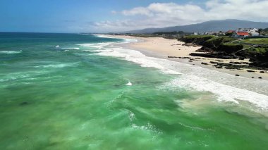 berrak suları ve yumuşak kumlu kıyıları olan sakin bir plajın çarpıcı hava görüntülerini tecrübe edin.