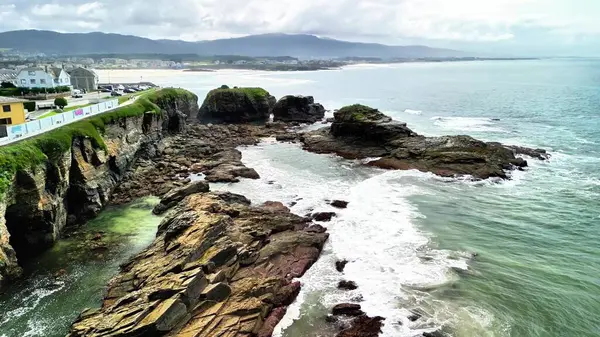 Nefes kesen bir hava perspektifi engebeli kayalık kıyı şeridi mavi dalgalar ve cennet gibi bir plaj.