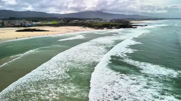 Yatıştırıcı sahil dalgalarının, kumlu kıyıların ve arka planda yemyeşil tepelerin güzel hava görüntüleri..